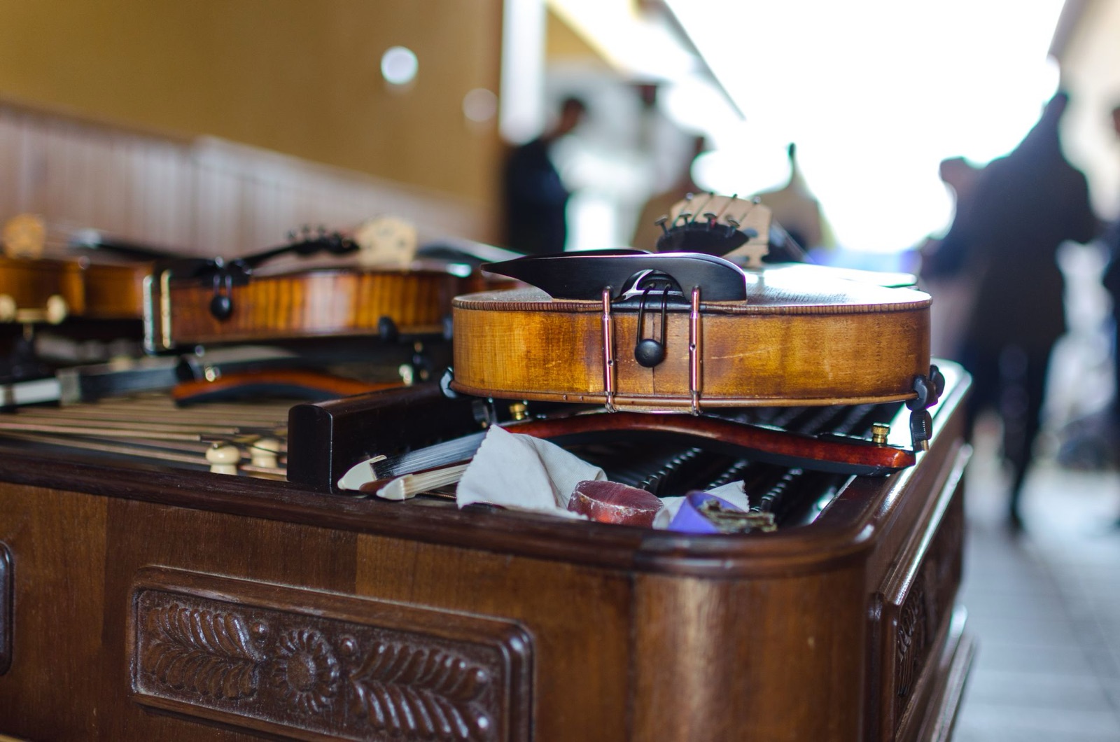 Two violins resting on a piano representing thoughtfully curated wedding music packages.