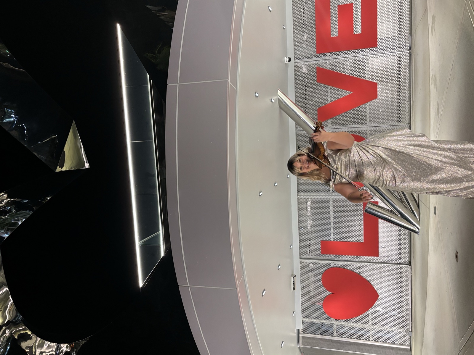 Violinist of Luxe Harmony playing her violin in front of LOVE sign, offering information about wedding violinist prices.